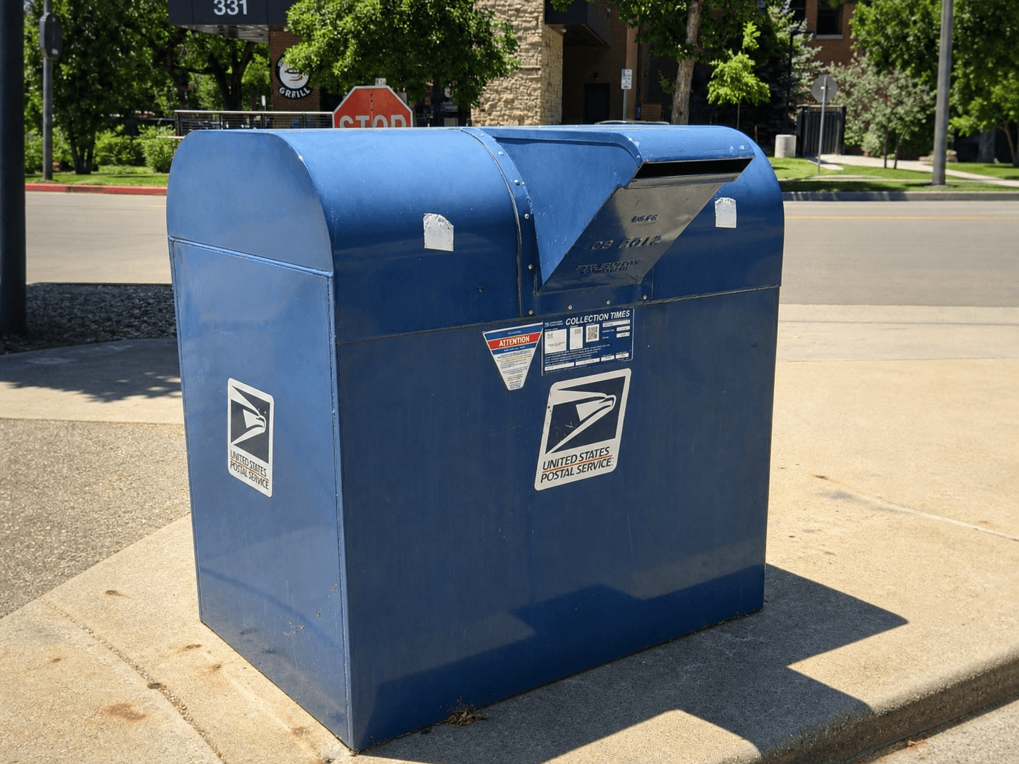 USPS blue collection box with its collection-times label displayed on the front