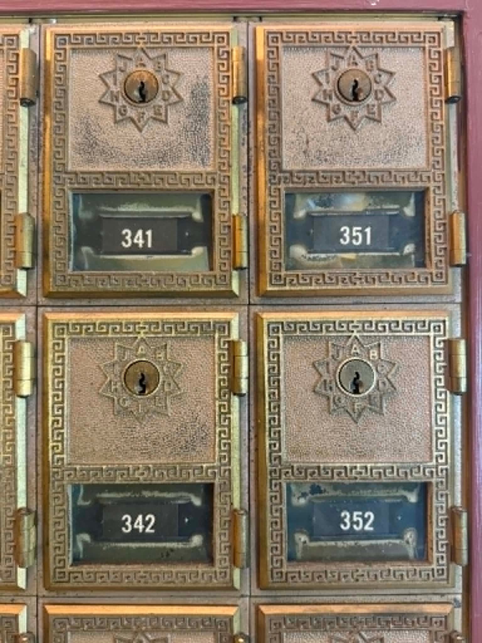 Close view of ornate brass PO Box doors inside an older Post Office