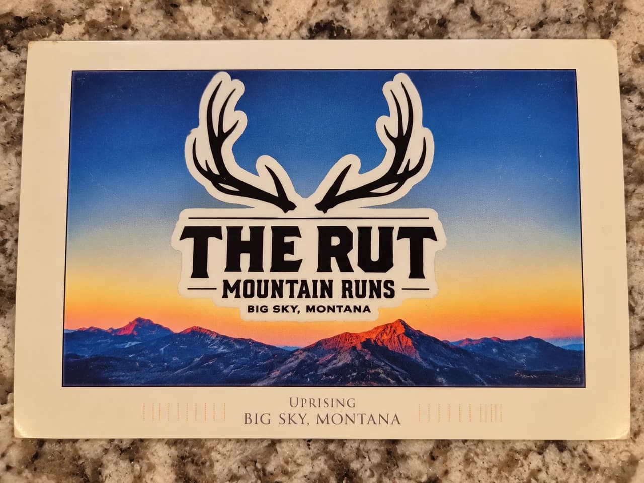 The picture side of a Big Sky, Montana postcard showing mountains at sunset