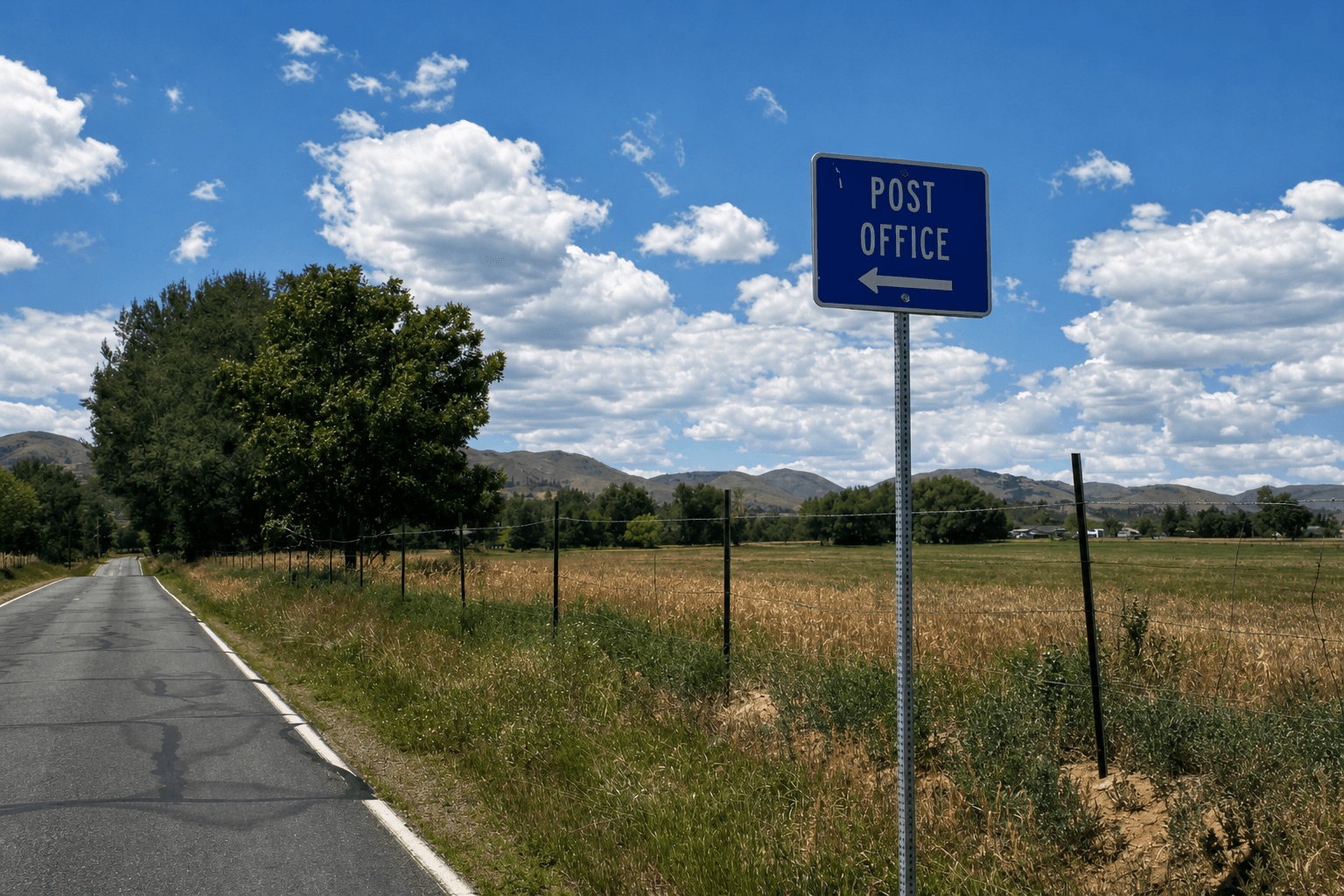 A rural road and Post Office direction sign in mountain country