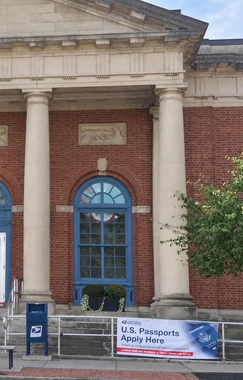 USPS Post Office entrance with a blue collection box and a U.S. Passports Apply Here banner