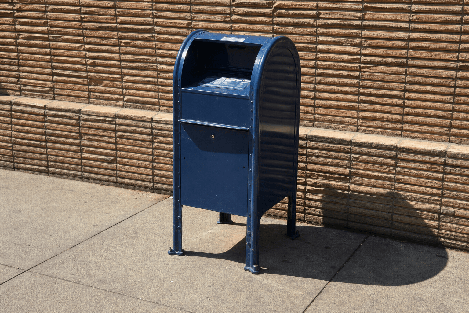 Blue mail collection box outside a brick building