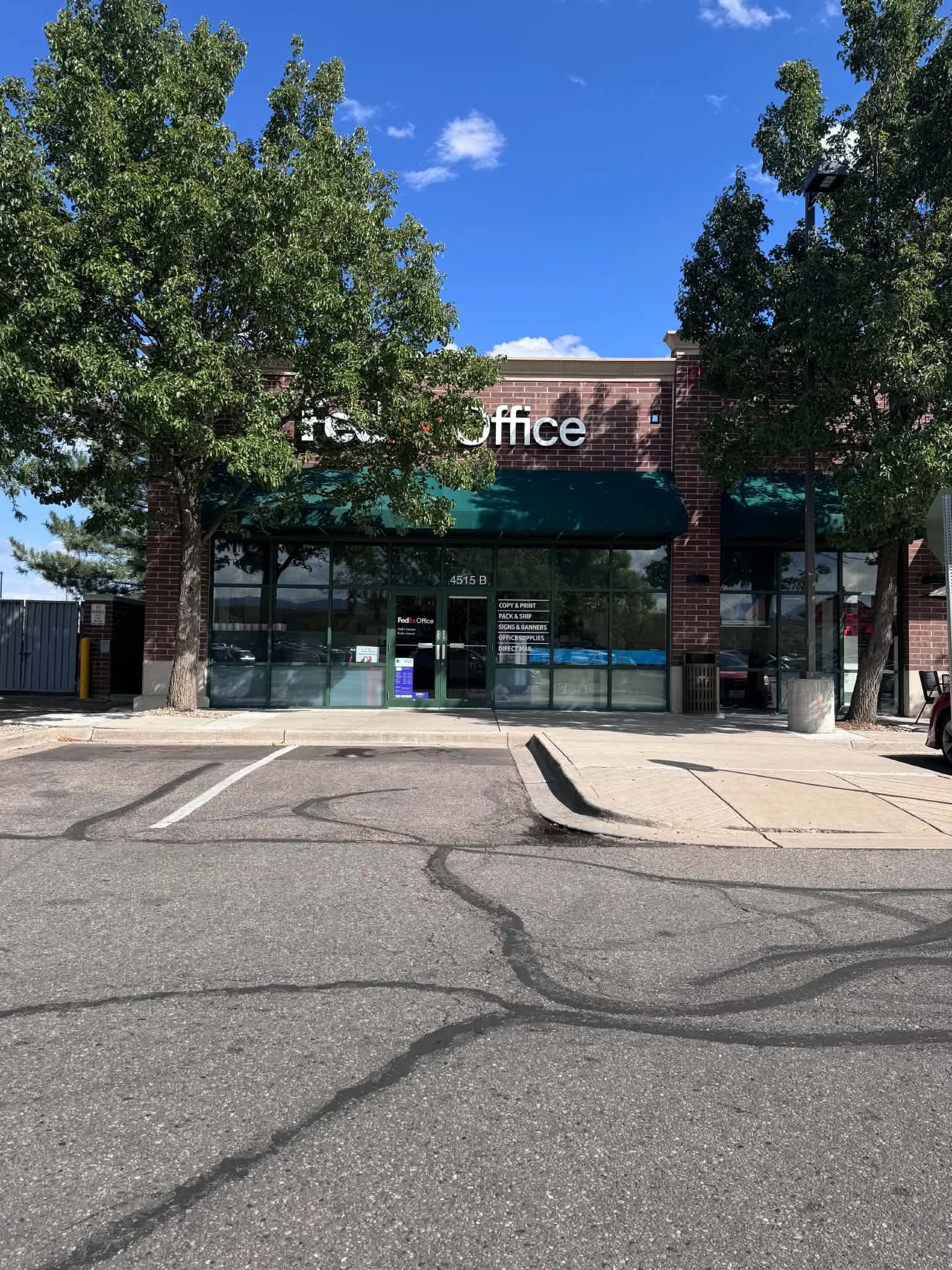 FedEx Office storefront with trees partially covering its sign
