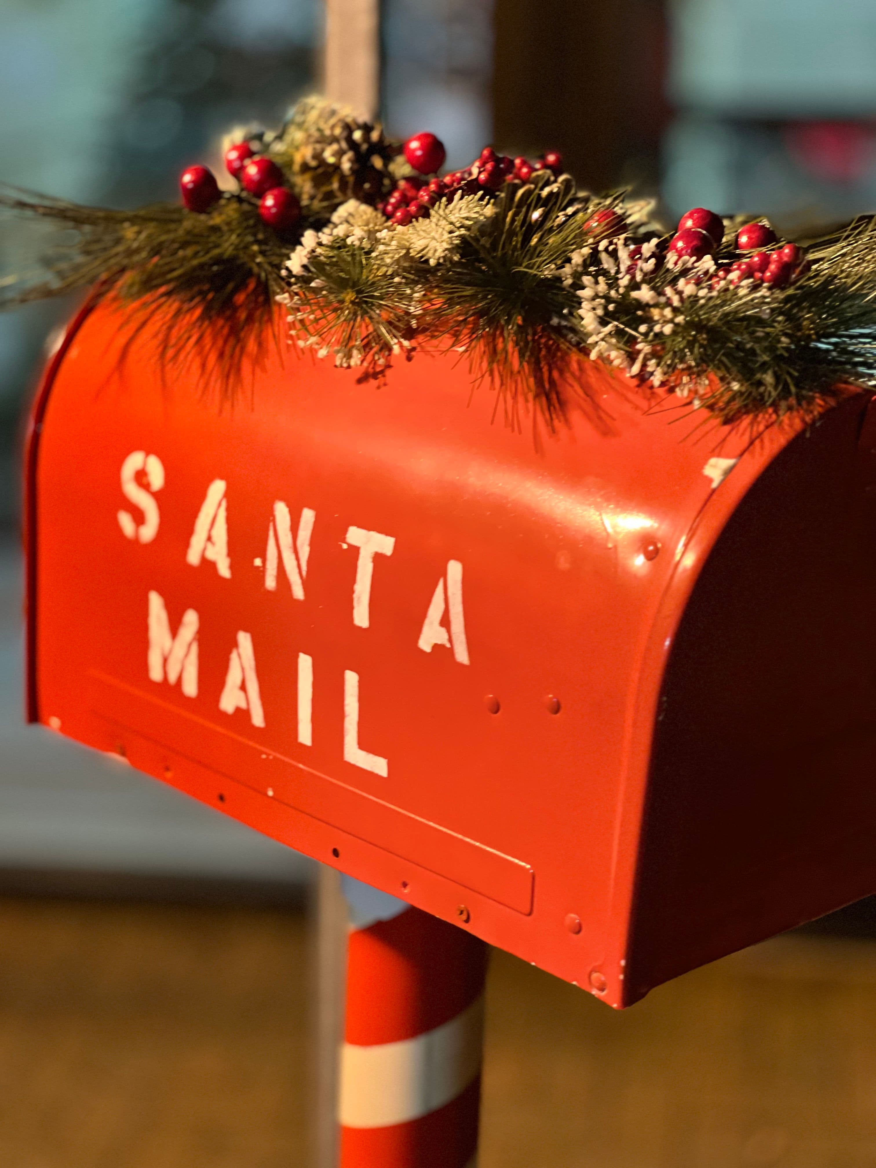 Red Santa Mail mailbox decorated with evergreen branches and red berries